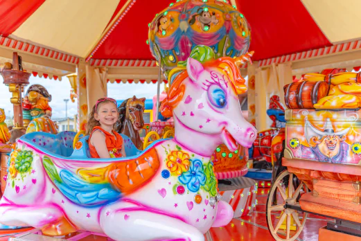 Petite fille souriante sur un manège licorne coloré au camping VAGUES OCEANES Licorne à Dunkerque (59). Petite fille souriante sur un manège licorne coloré au camping VAGUES OCEANES Licorne à Dunkerque (59).
